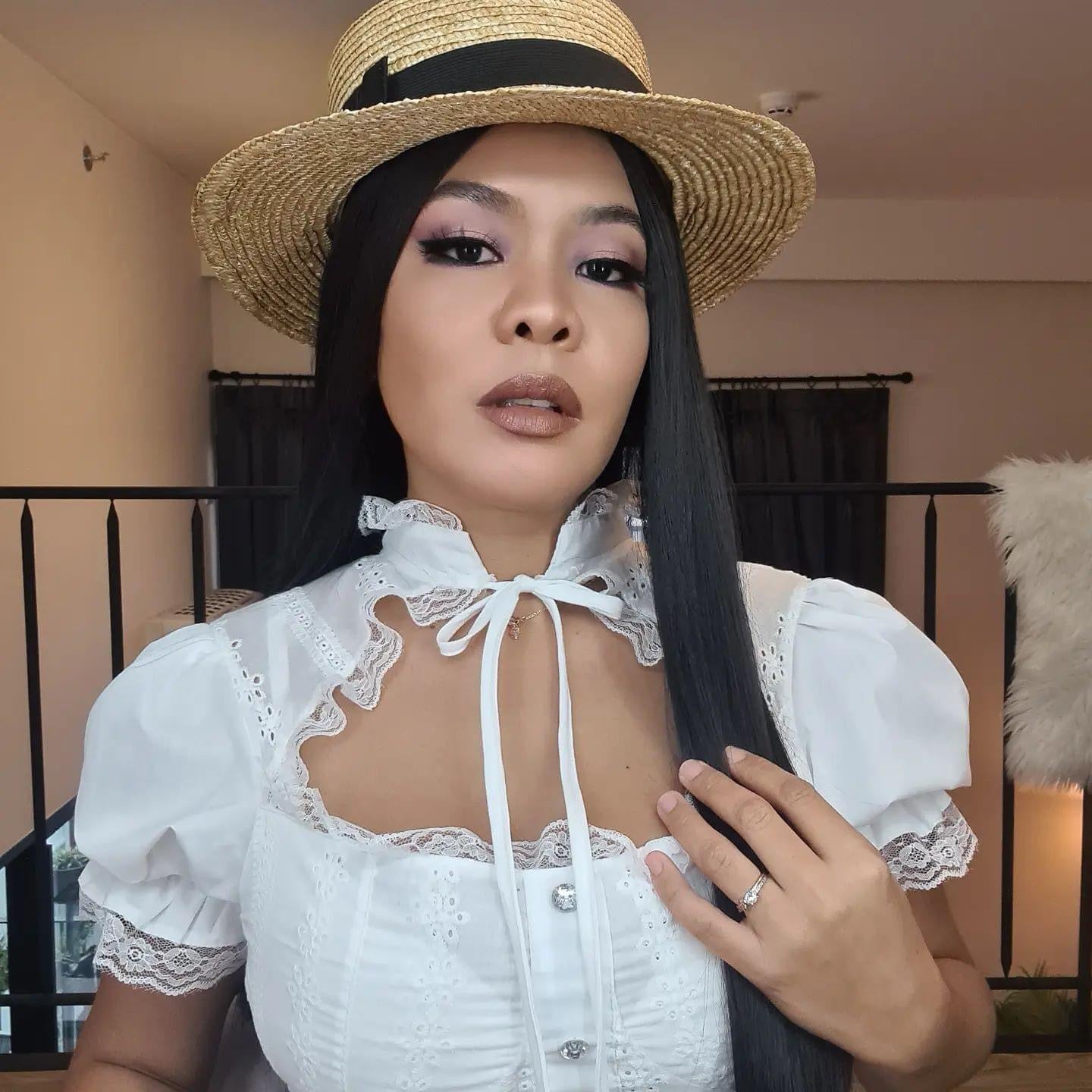Diana wearing a straw hat and a white lace blouse
